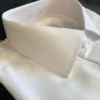 White dress shirt with a standard collar, folded on a plain background.