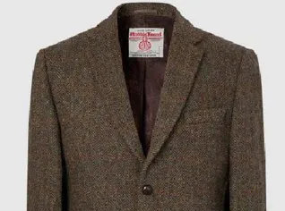 Harris Tweed Jacket. Brown jacket featuring two button fastening, vented cuff and elbow patch details. Product image on a plain background.